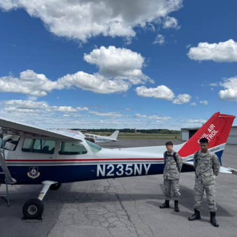 two students standing in front of an airplane