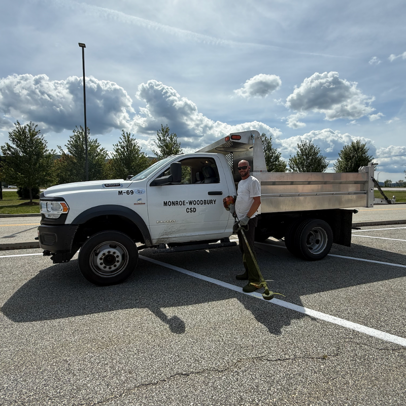 man with a white shirt holding a weed whacker