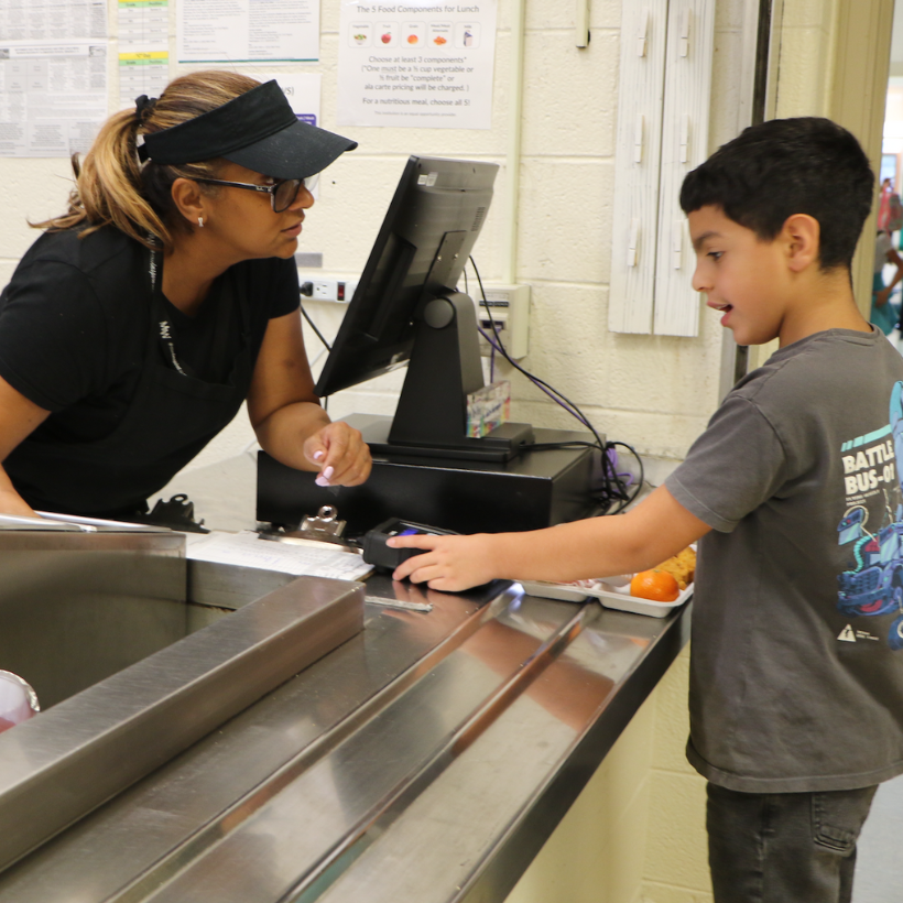 woman in all black helping student in a grey shirt get a lunch plate