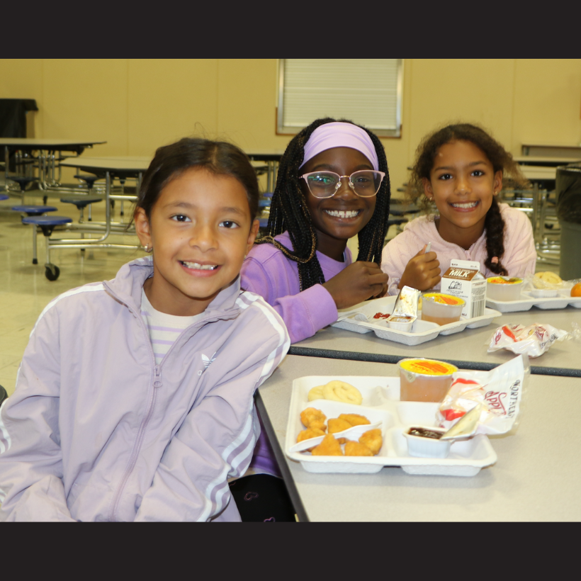 students wearing pink and purple shirts eating lunch 