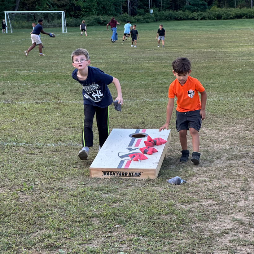 two students playing cornhole 