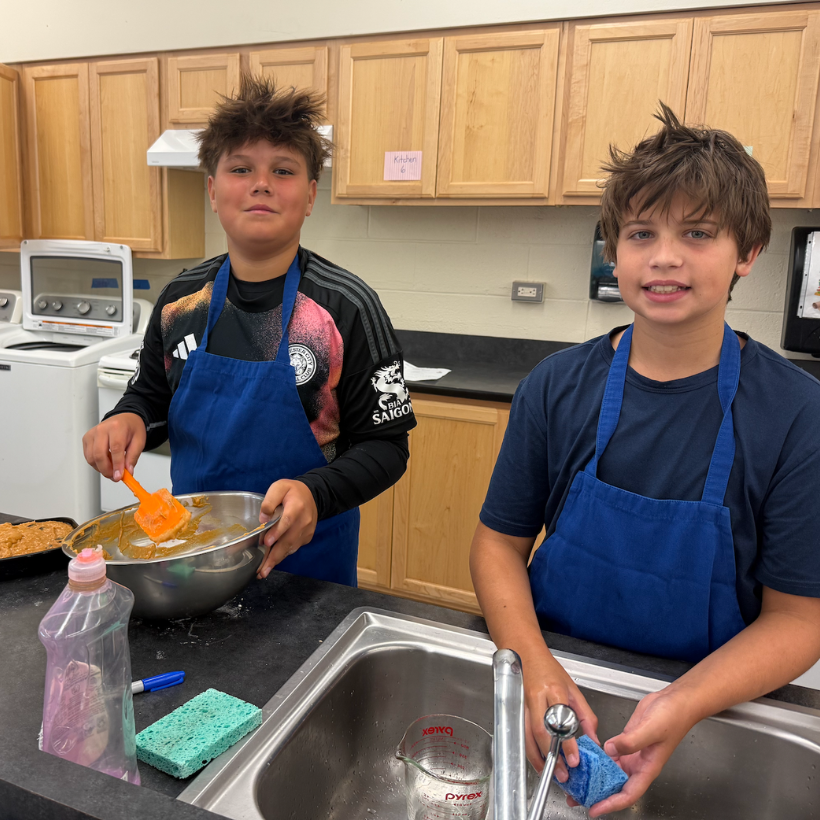 two students wearing blue aprons and black shirts