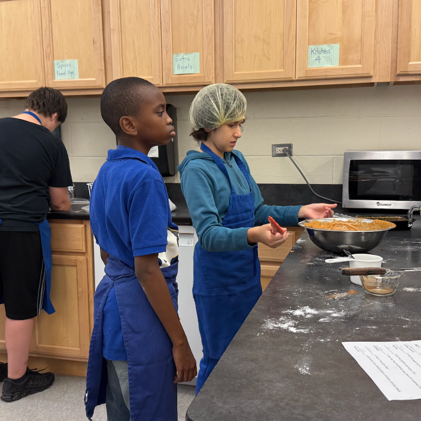 two students wearing blue aprons and blue shirts