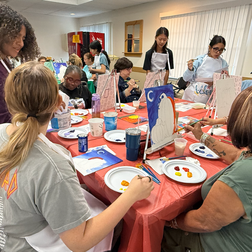 students and seniors at an orange table painting 