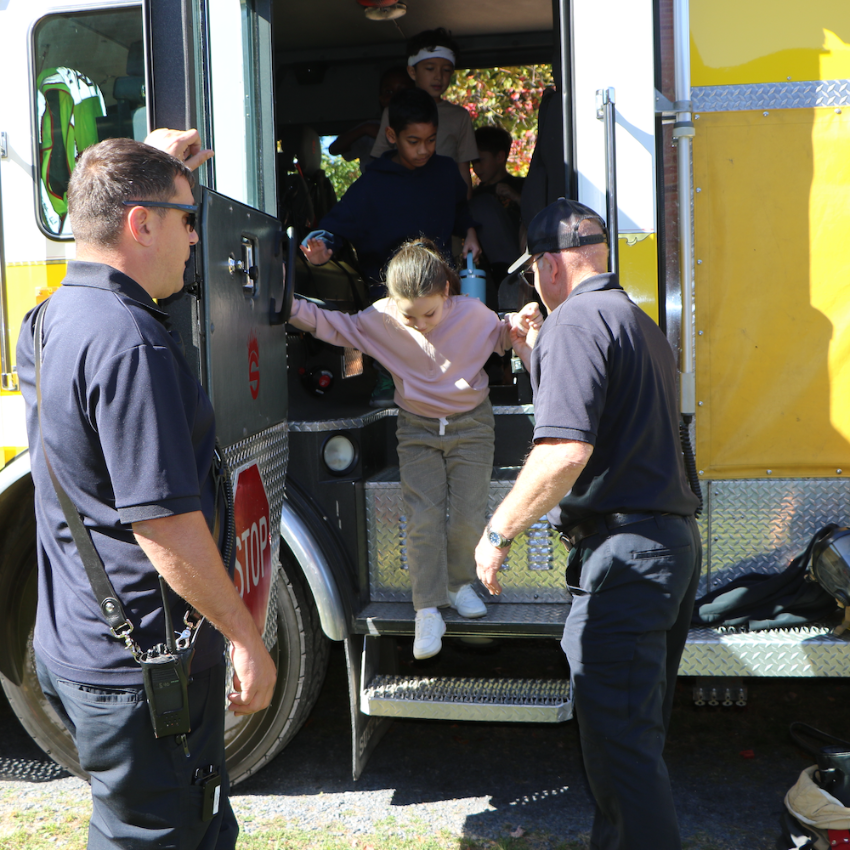 student stepping off firefighter truck 