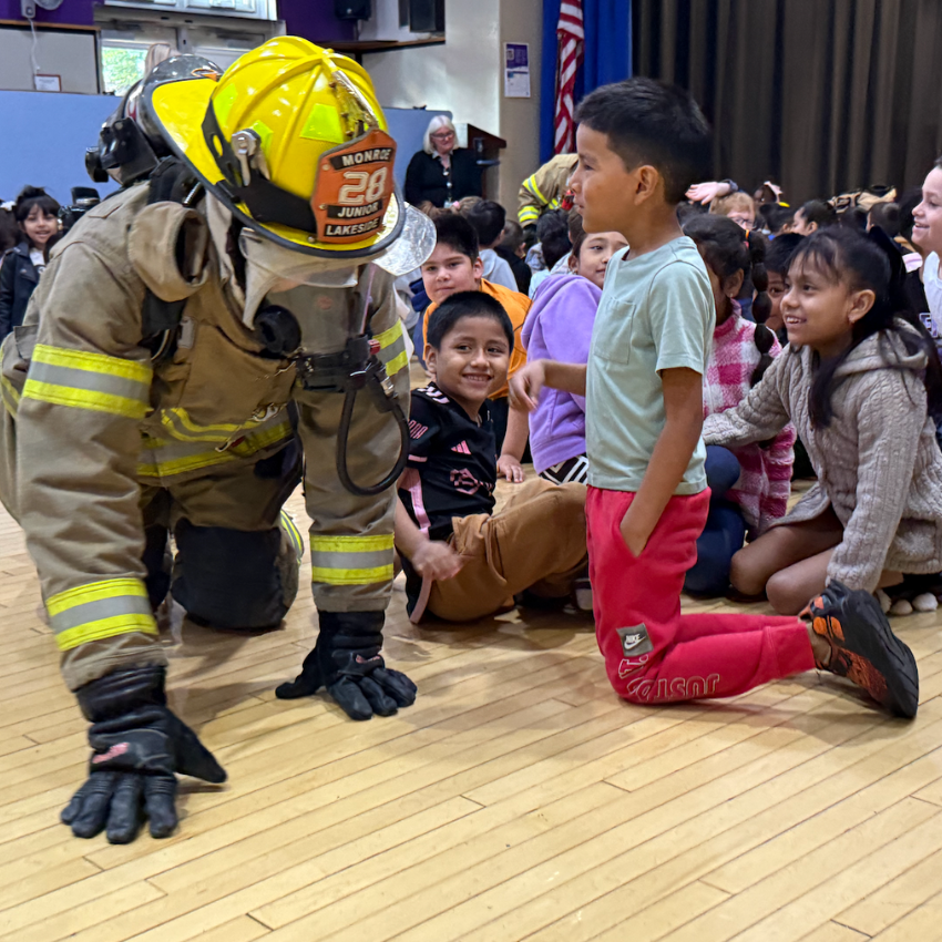 fire fighter crawling next to student with red pants 