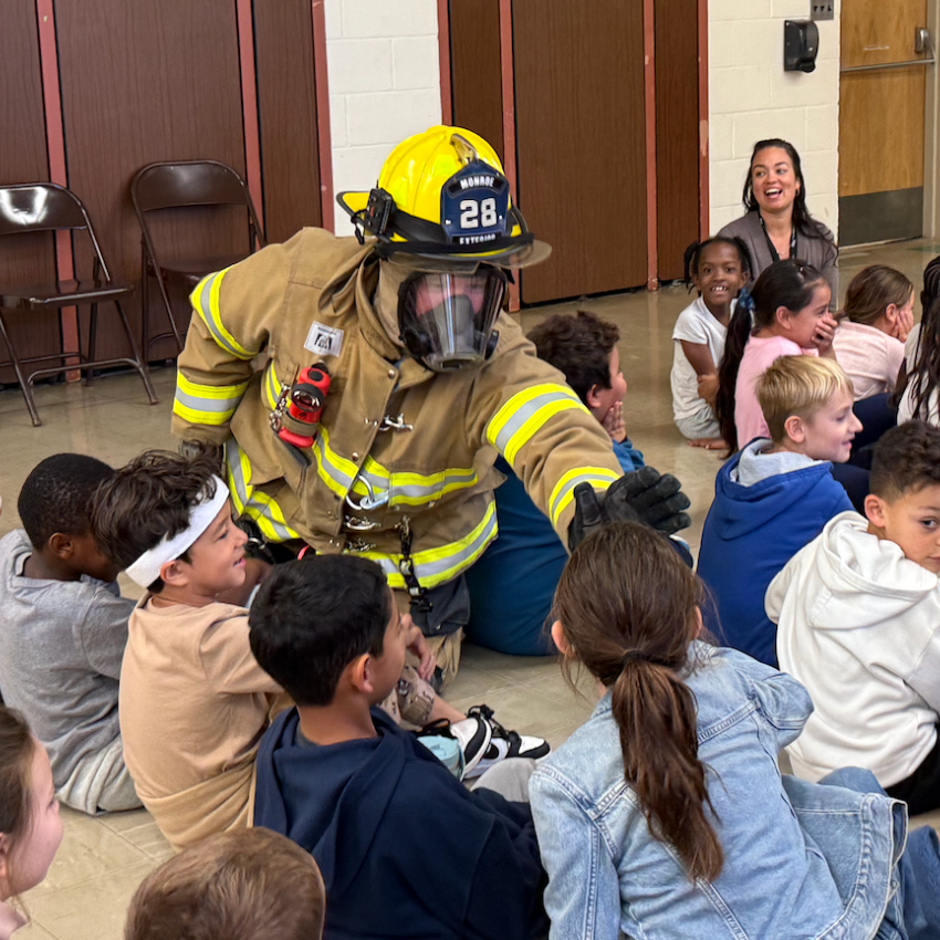firefighter with yellow hat giving student a high 5