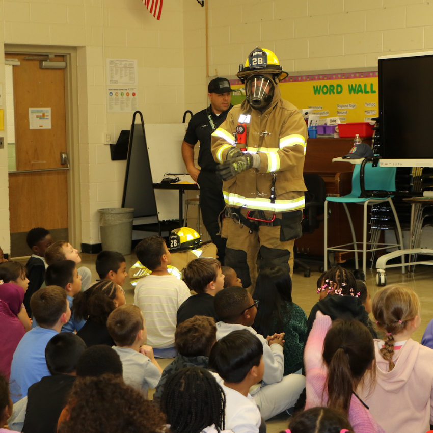 students sitting listening to firefighter in uniform 