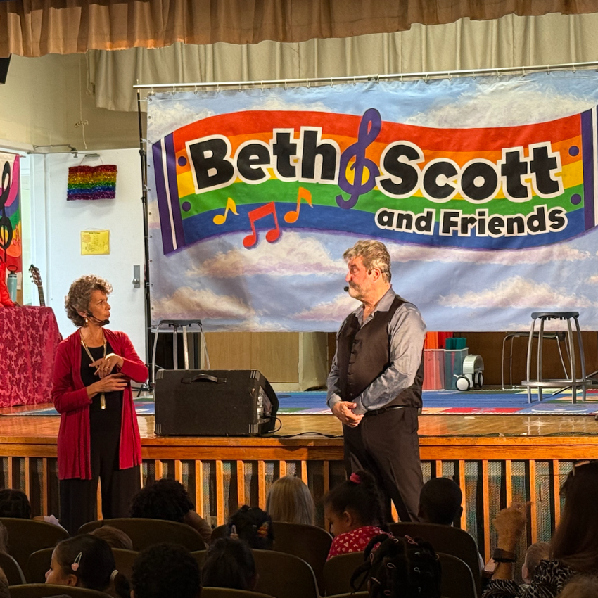 a woman with a red sweater and a man with a black shirt standing in an auditorium 