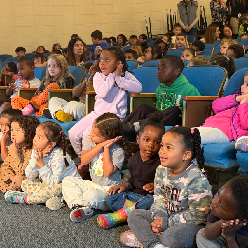 students sitting on the floor in an auditorium 