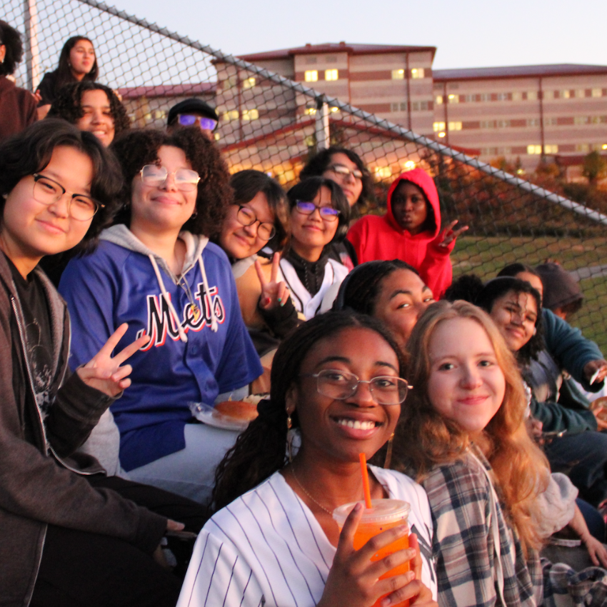 students sitting in the bleachers smiling