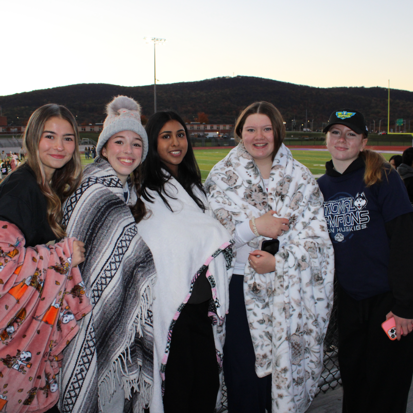 five students with blankets smiling 