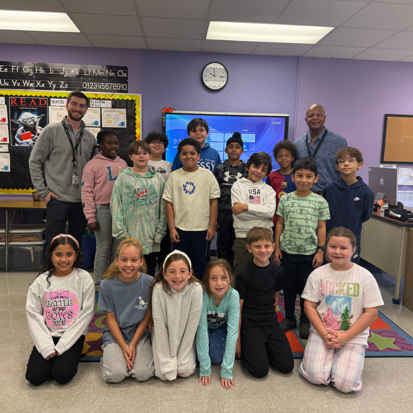 students and teachers sitting adn standing in a classroom 
