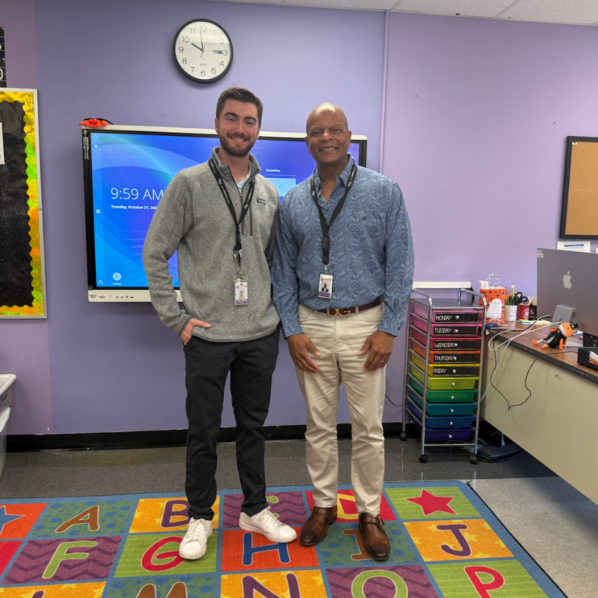 two men standing together on a rug with letters 