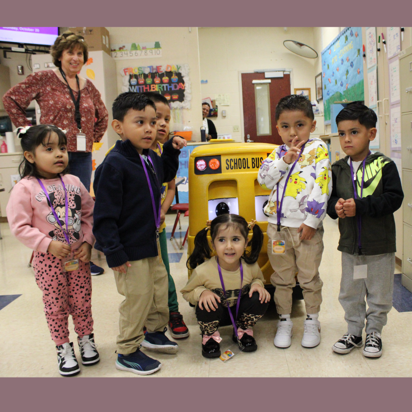 students standing around a toy school bus 