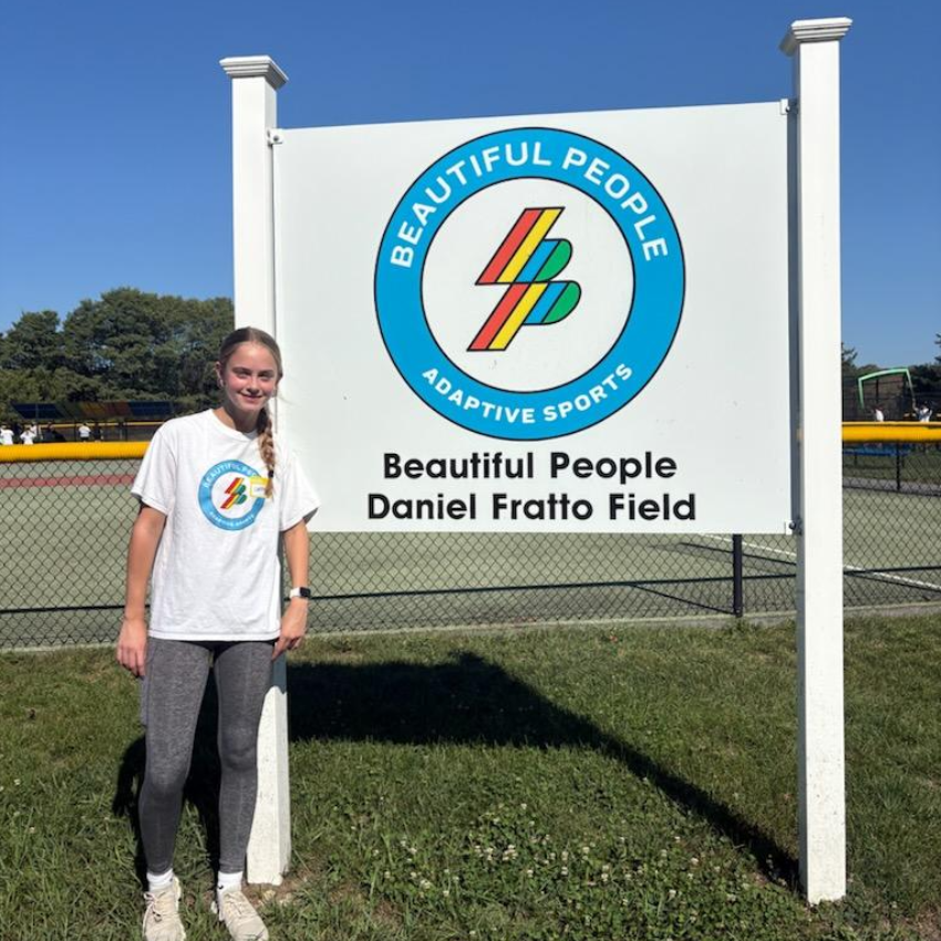 one student standing in front of large white sign with a blue circle