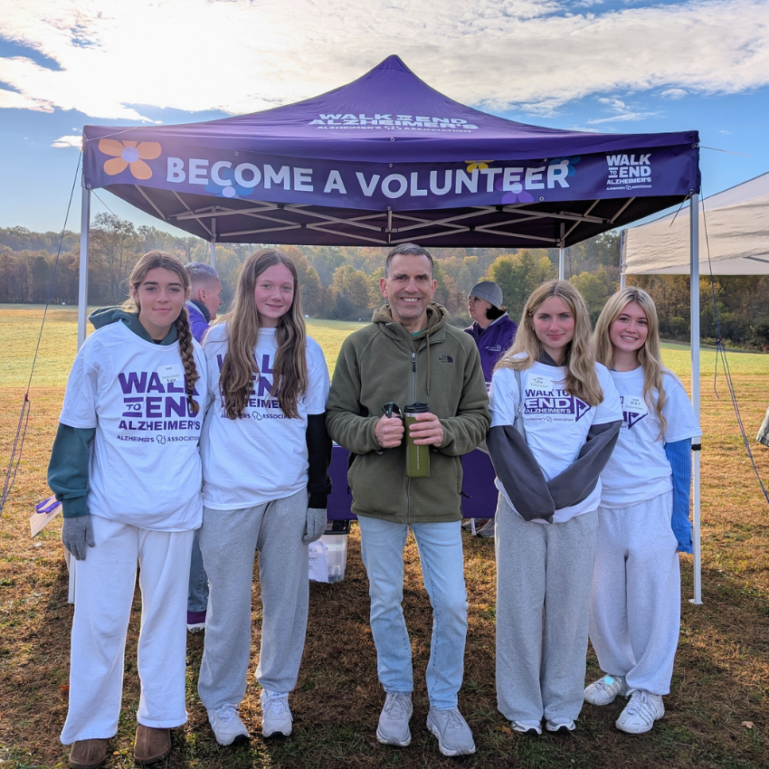 five people standing in front of a purple tent 