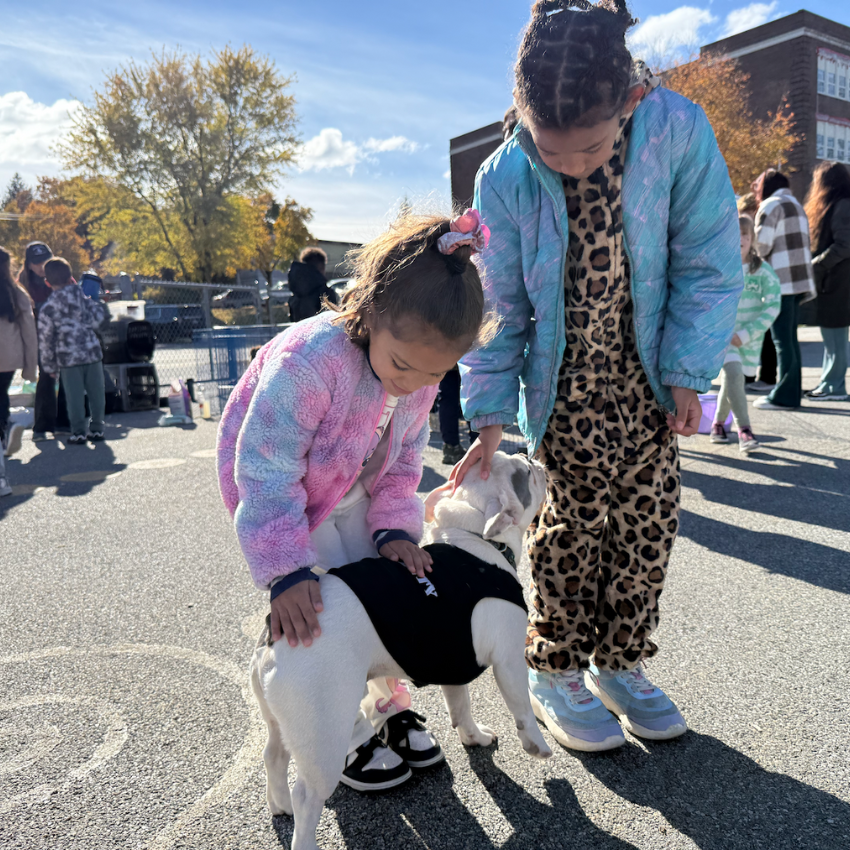 two students petting a white dog