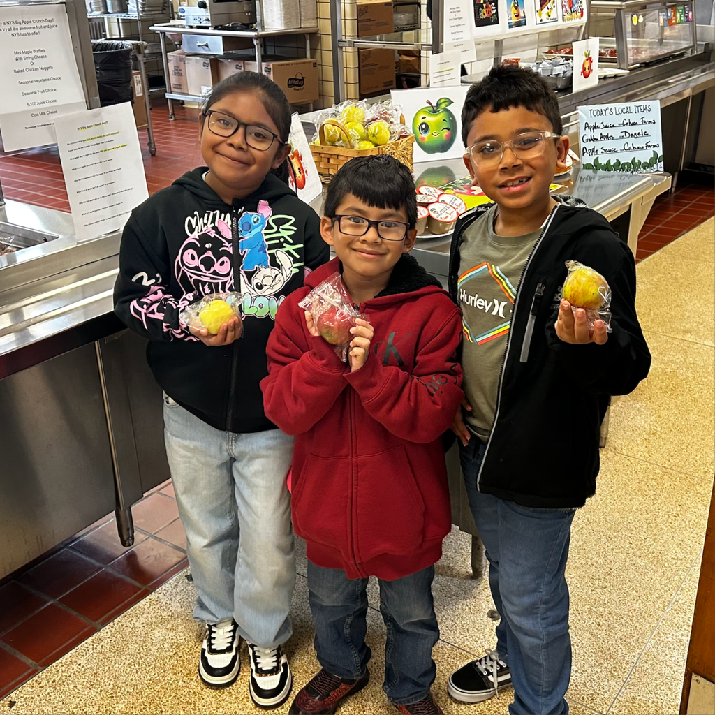 three students holding apples