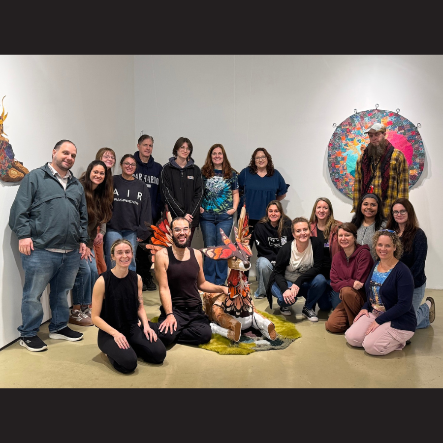 group photo of people smiling around art deer