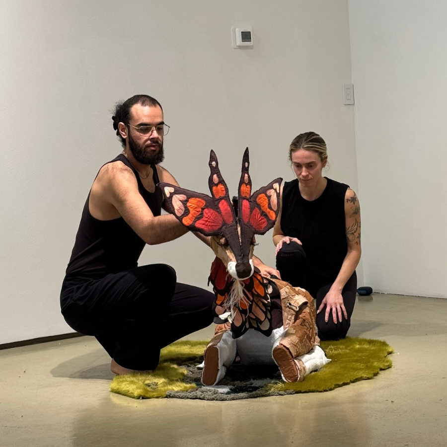 photo of two people wearing black and holding a decorative deer