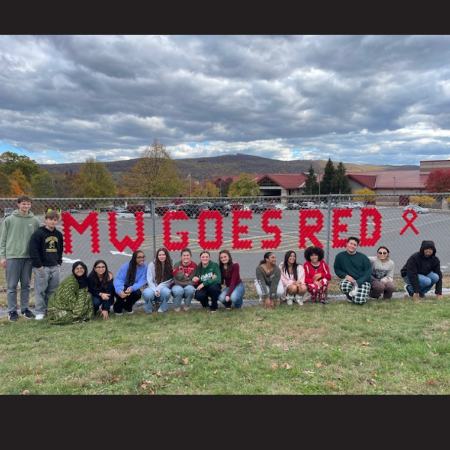 students standing in front of a red sign that says M-W goes red