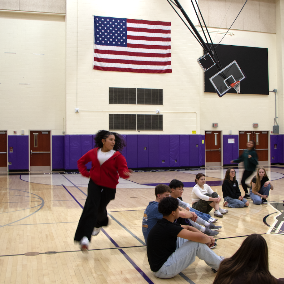 student with a red sweater running in gym