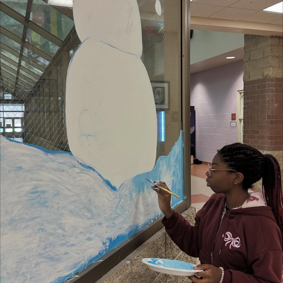 student painting a snowman on a window