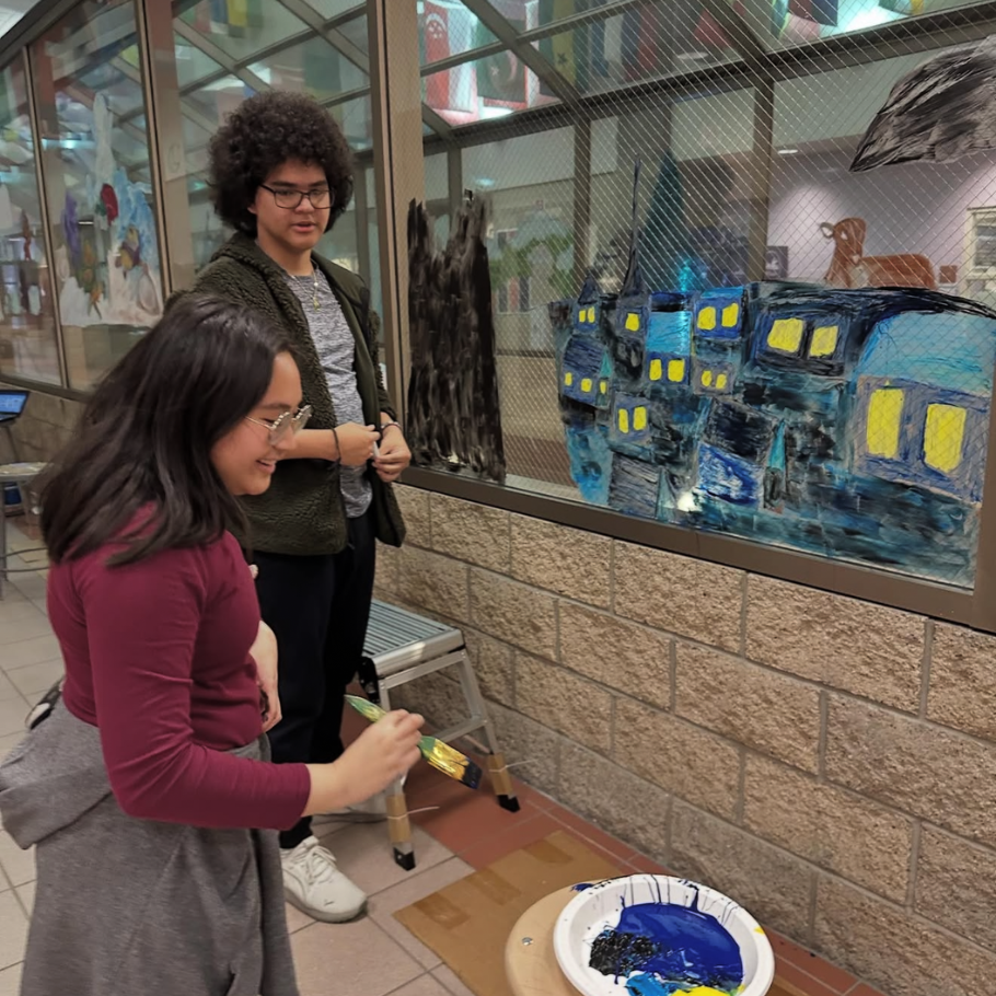 two students holding paintbrushes