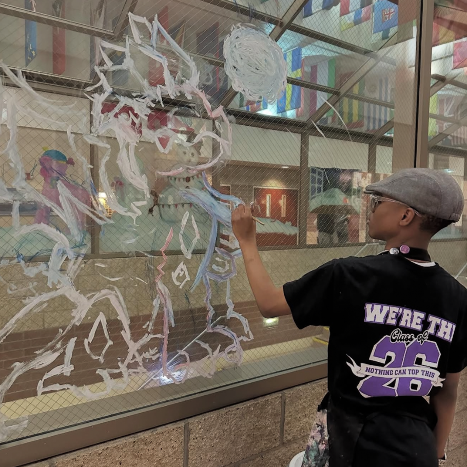 student with a grey hat painting windows 