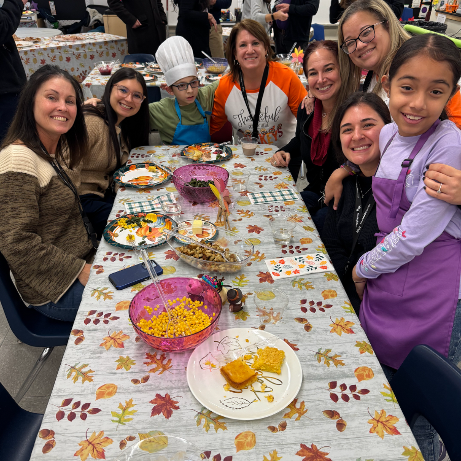 people sitting at a table with food and table cloth with leaves