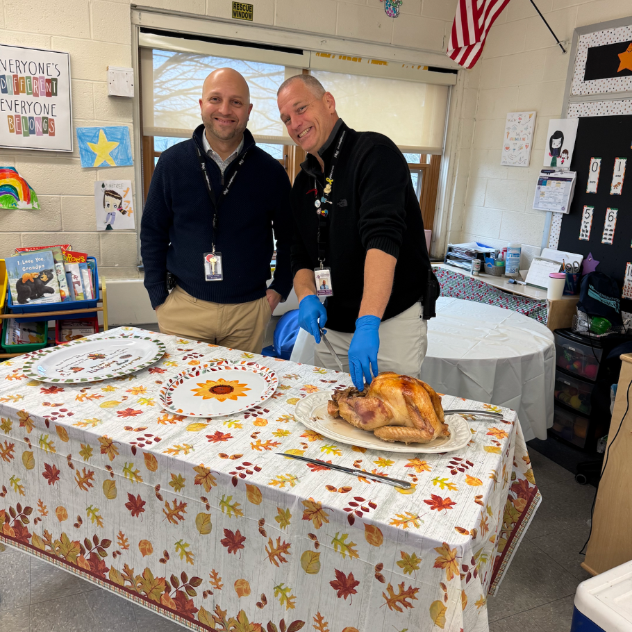 two men with black shirts carving a turkey