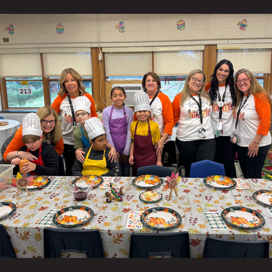 table with pumpkins on plates an paper turkey  with people standing in back of table 
