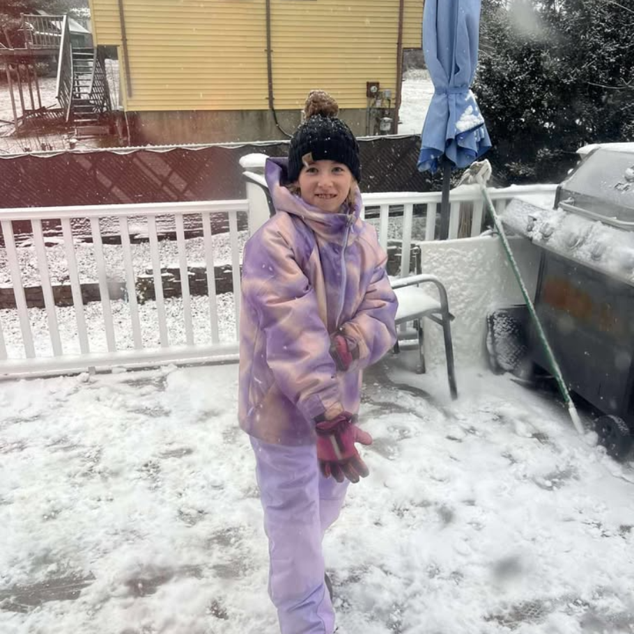 student wearing all purple snowsuit standing in snow