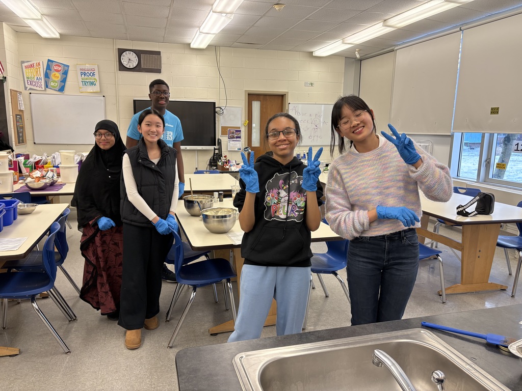 students with gloves on making lasagna