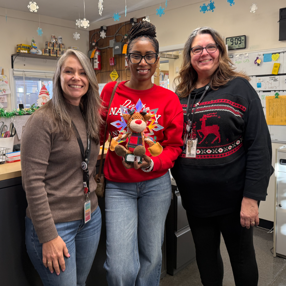 three women standing with a reindeer trophy