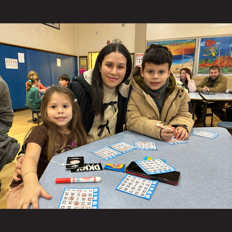 three people sitting at a blue table with bingo cards