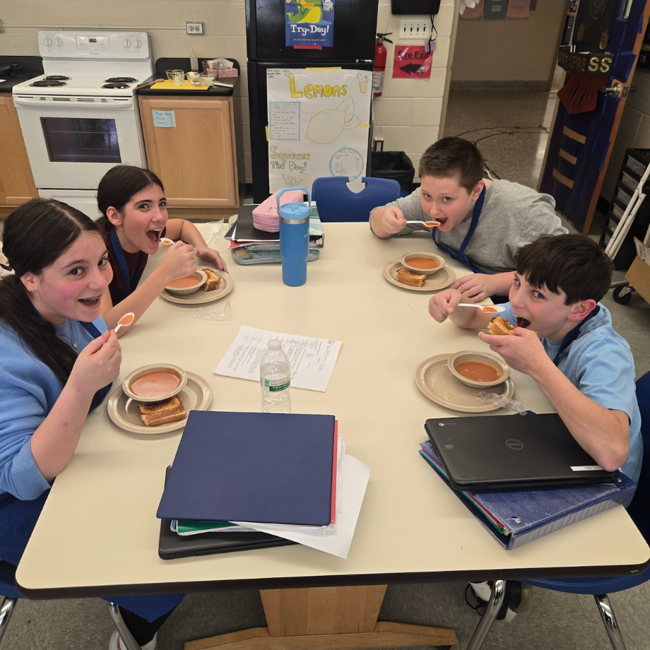 students sitting at a table eating soup