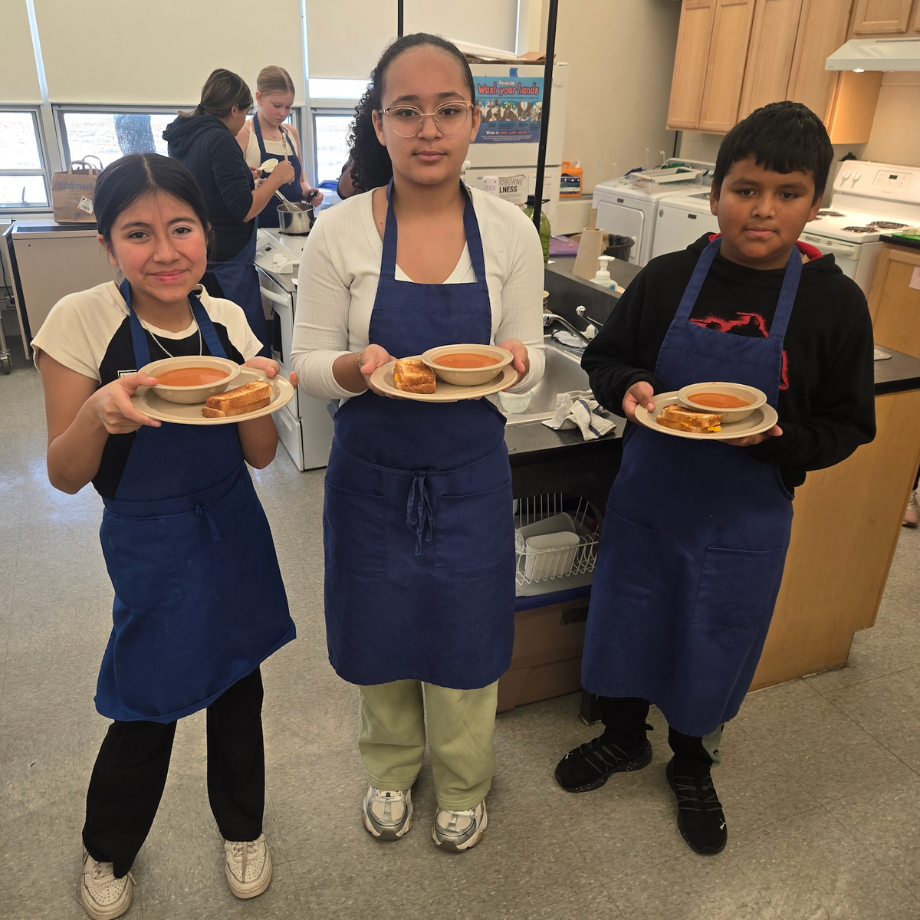students holding bowls of soup and sandwiches