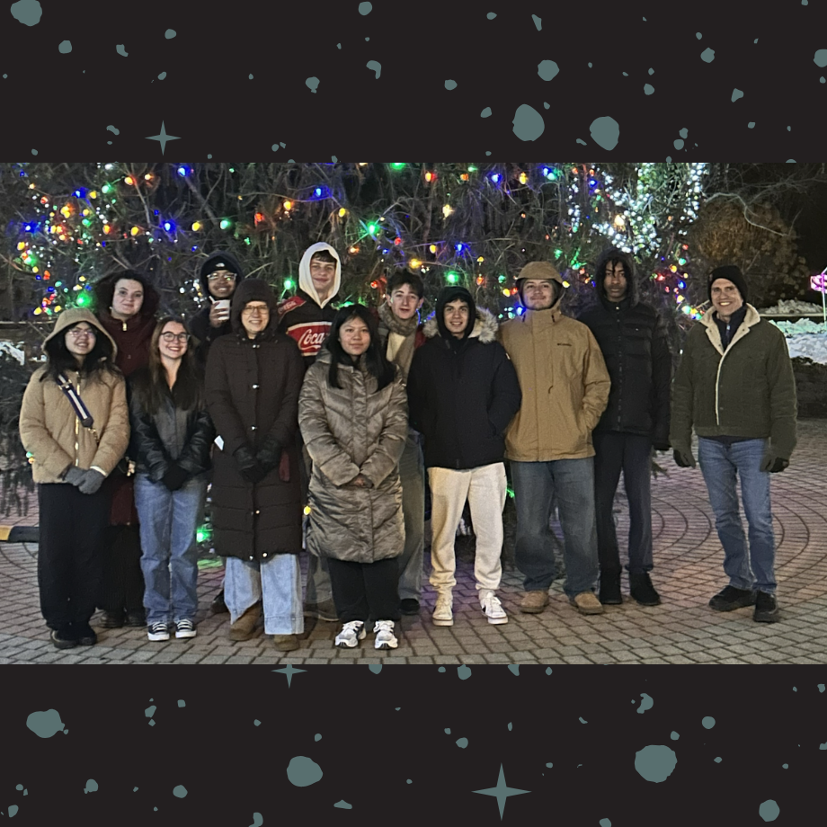 students standing outside in front of a Christmas tree