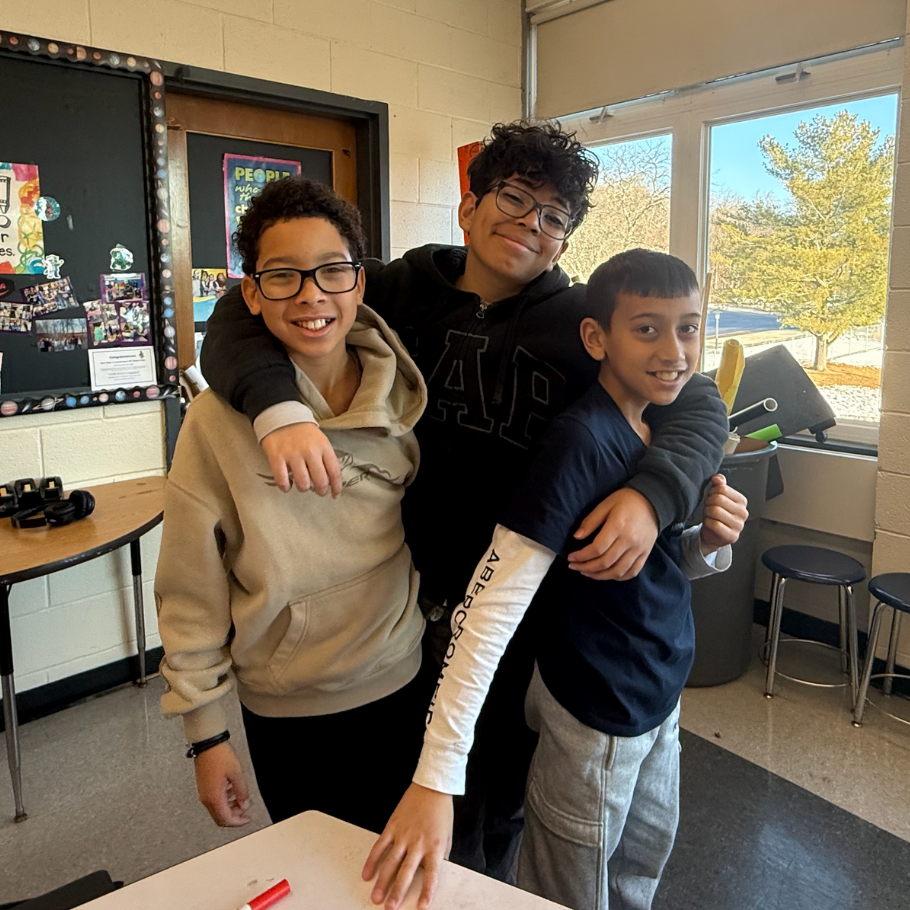 three students wearing blue and brown sweaters 