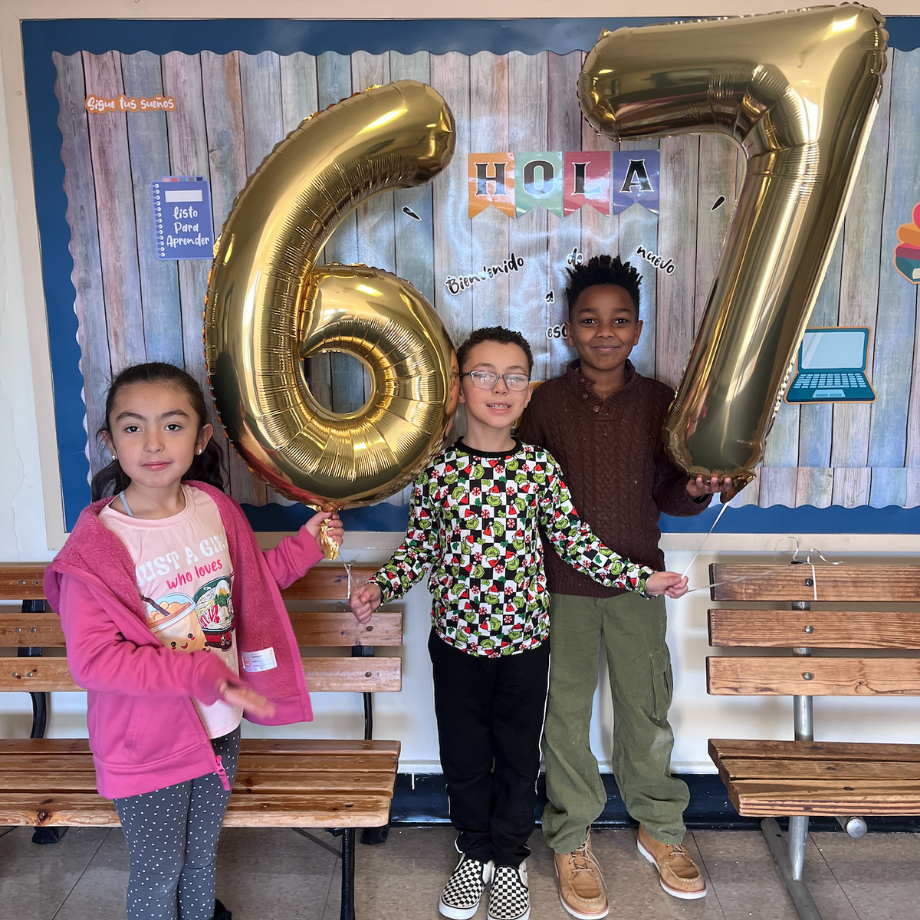 three students standing with balloons numbered 6 and 7