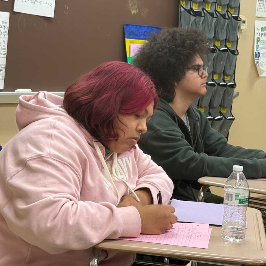 student with pink sweatshirt sitting at desk 