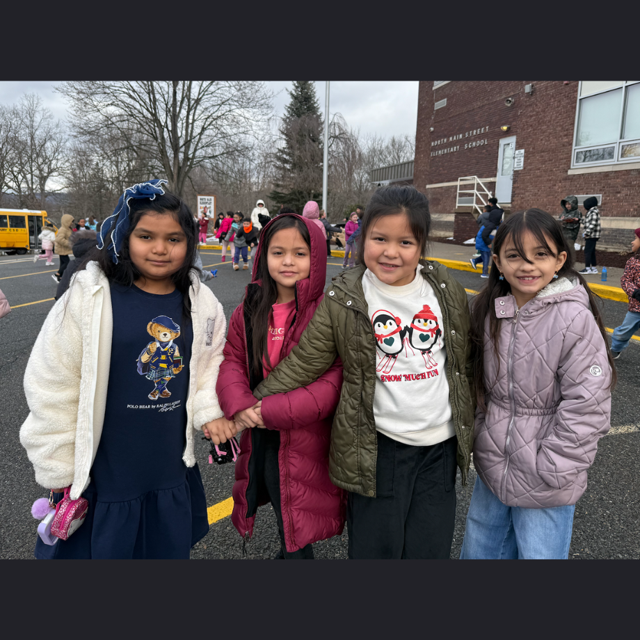 four students standing in front of a school
