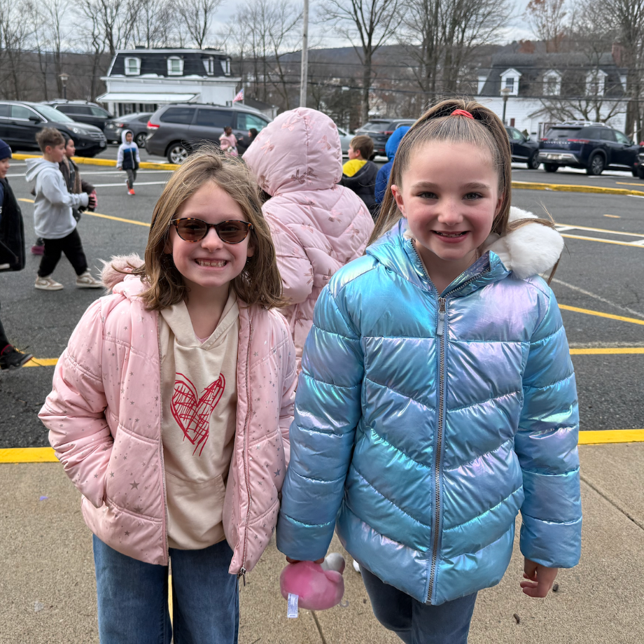 two girls with pink a blue coats standing outside
