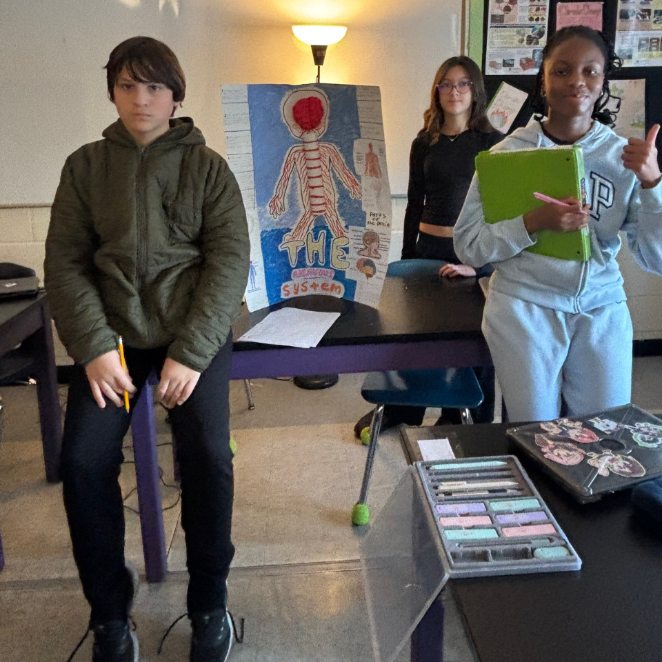 three students standing in front of a table 