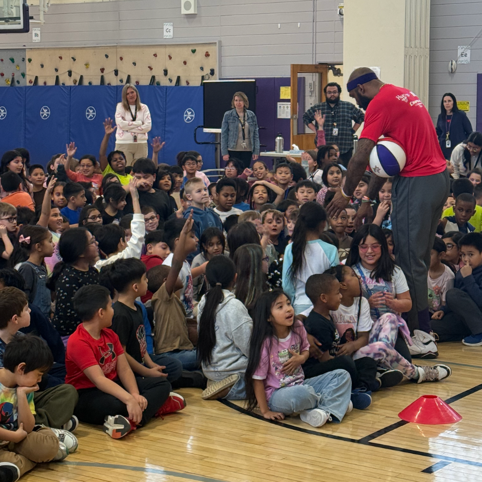 man holding a basketball with students 