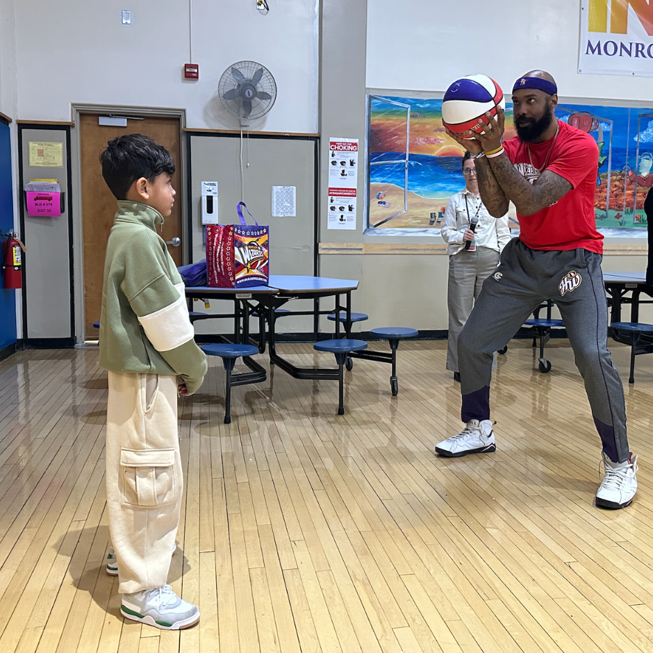 man holding a basketball next to student 