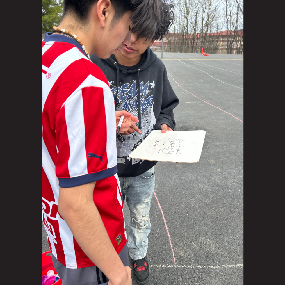 two students holding a white board 