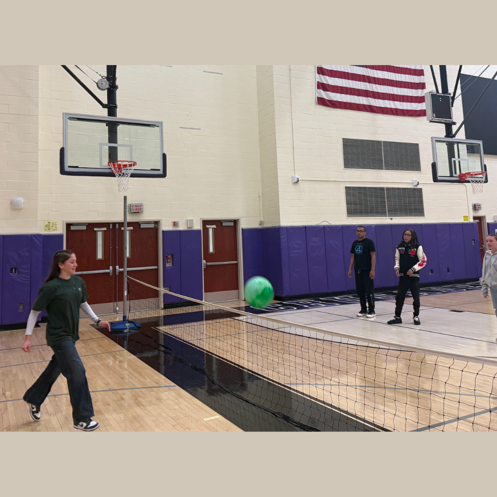 student hitting a ball over a net